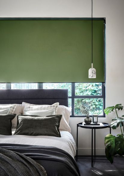 Monochrome bedroom with a dark green blind and plants fitting the colour theme 