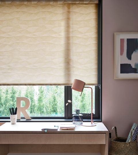 a blush pink study space with a light yellow patterned blind and wooden furnishings