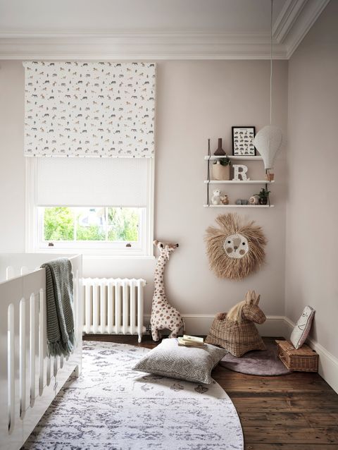 a neutral children's bedroom with a white and giraffe, elephant, lion and plant print blind and animal toy furnishings