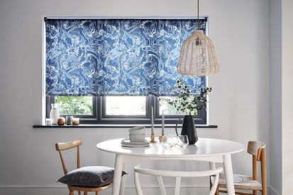 A monochrome dining room with a marble blue blind and wooden furniture