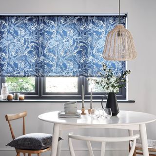 A monochrome dining room with a marble blue blind and wooden furniture