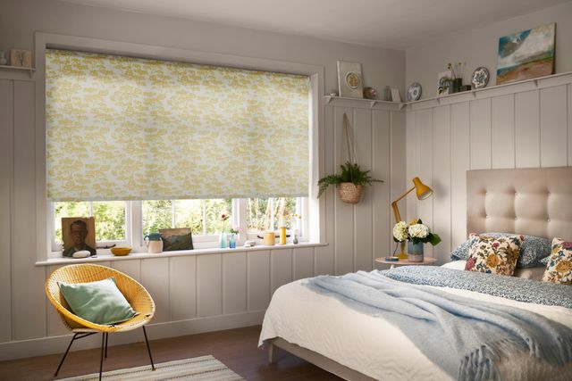 A warm bedroom with a white and yellow blind and neutral furnishings