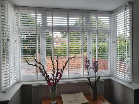 White faux wood blinds in dining room bay window