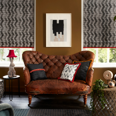 black and white roman blinds with a zig zag pattern fitted to a tall window in a living room with a brown leather armchair