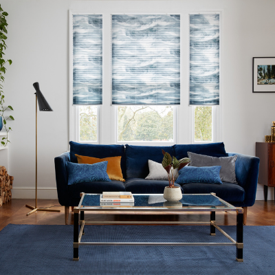 blue white and grey venetian blinds in living room with a blue rug, blue sofa, glass table and white walls and windows