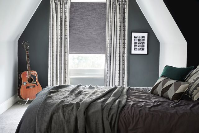 Hayden Graphite roller blinds displayed alongside Vivado Ash curtains on a bedroom next to a guitar 