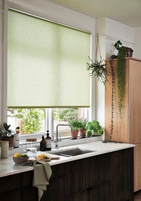 Conscious Lime roller blind made of recycled polyester displayed in a kitchen surrounded by greenery of plants and the kitchen sink