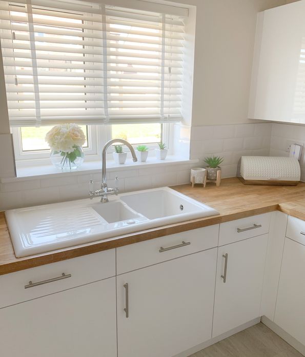 White, wooden blinds in a white and light brown kitchen