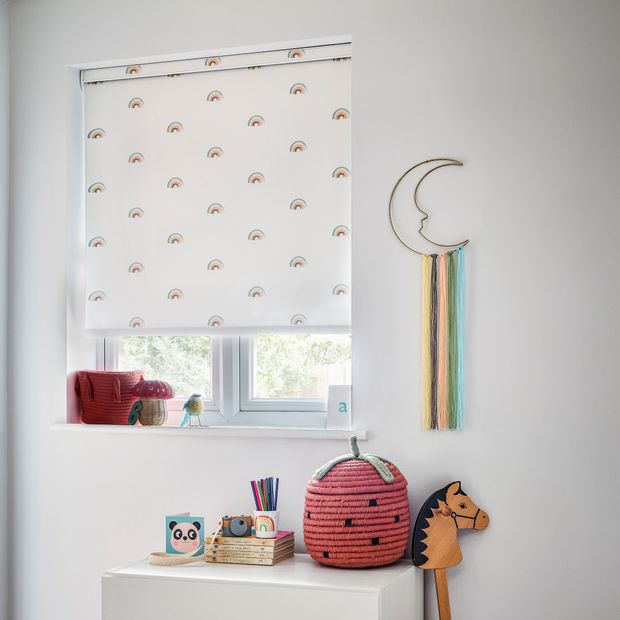 white roller blind with mini rainbows on in a childs bedroom window with childrens decoration and a hobby horse
