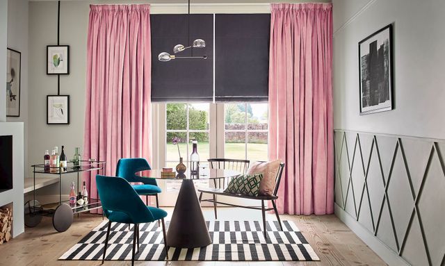 Velvet, rose pink curtains over a dark roman blind in a modern living room