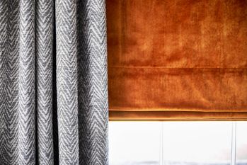 Burnt orange, velvet curtains under grey, patterned curtains