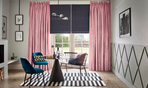 Velvet rose pink curtains over a dark roman blind in a modern, bright living room
