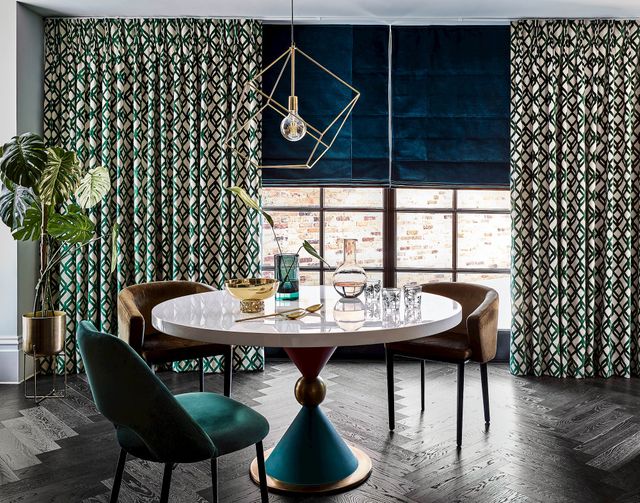 Velvet teal roman blind under white and green patterned curtains in a dark, modern dining room