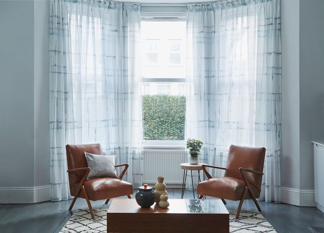 Adrift Ink Wash Voile Curtains in 3 sided bay window with 2 tan orange armchairs