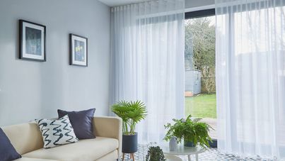 Clarity white voile curtains against wide floor length windows leading to garden