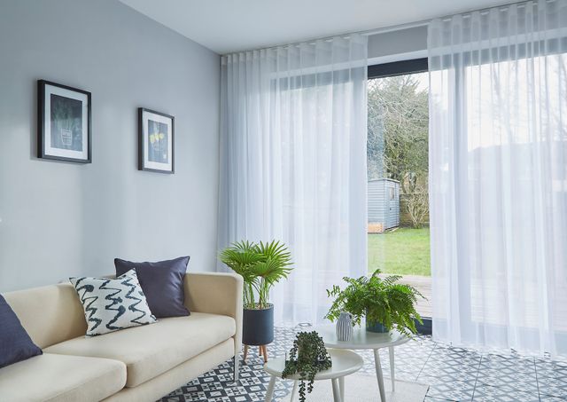 Clarity white voile curtains against wide floor length windows leading to garden