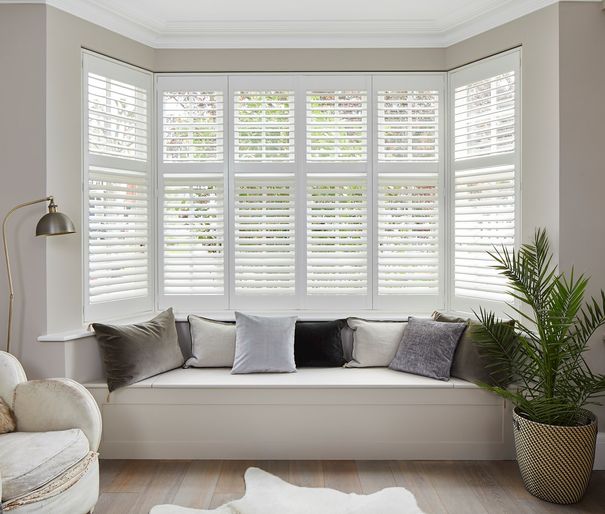 Richmond Silkwhite Shutters in a lounge window with white furniture 