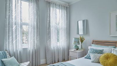 silver and white voile curtains in blue bedroom beside white table and blue bed