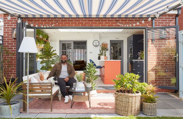 Man sat in lavish outdoor patio area with Rome blue awnings fully outstretched above