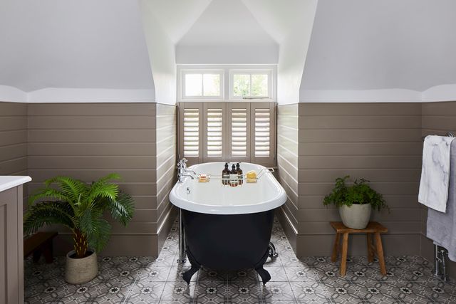 Henley brown grey shutter in small bathroom window above large claw foot bath on pattern tiled floor