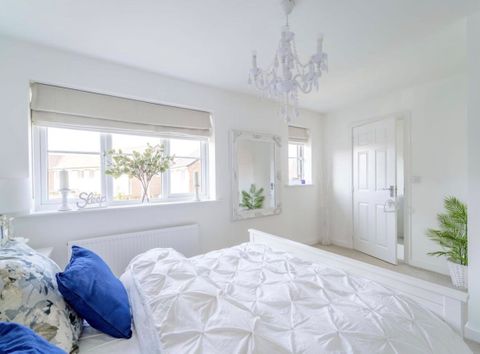 A modern, white bedroom with a cream roman blind