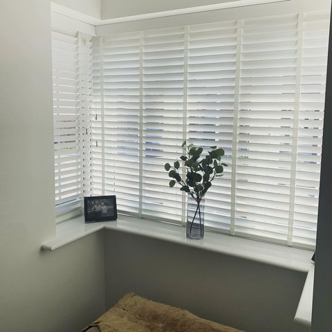 White Venetian blinds in a bright, white room with natural accents