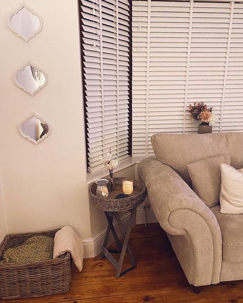 White faux wood venetian blind in 3 sided bay window with classic white and rustic wooden accessories 