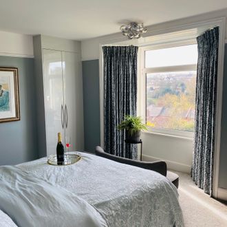 Navy and light blue floral print, pencil pleat curtains in a modern, muted bedroom