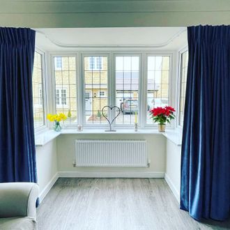 Deep Blue bay window curtains in a bright living room 