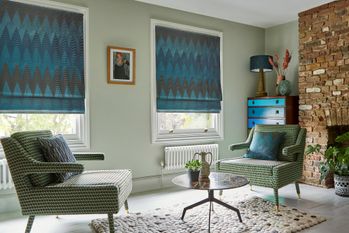 Zaha Deep Teal Roman blind on two windows in a lounge with two armchairs and a coffee table