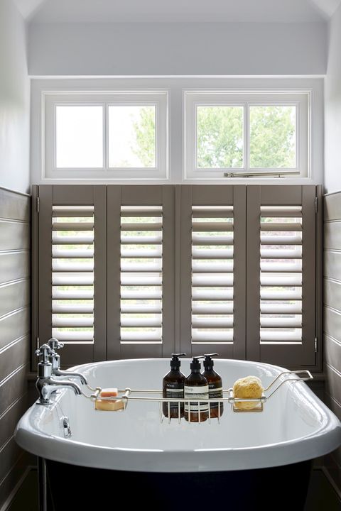 Cafe style shutters fitted to a bathroom window with a bathtub in the foreground