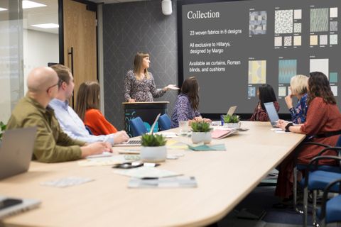 Women presents to colleagues in meeting room about a collection of fabrics