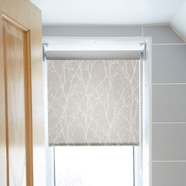 grey roller blind with white twigs patter on a bathroom window beside a light grey tiled wall