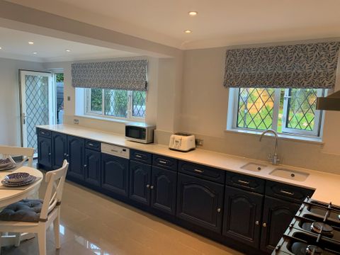Roman blinds in a kitchen with dark blue cabinets and white surface