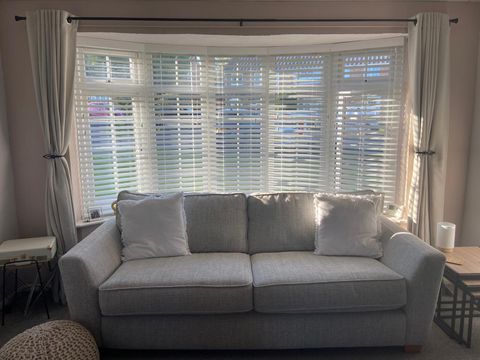 Venetian blinds in a bay window with a sofa in front of the windows 