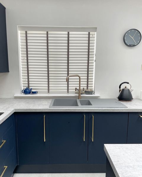 White venetian blinds in a white and navy kitchen
