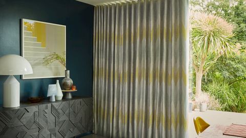 Zaha Sunrise Curtains fitted to a tall door window in a dining room with blue coloured walls