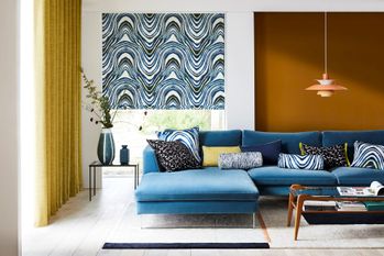 Blue and white patterned roman blind fitted to a window in a living room along with a yellow floor to ceiling curtain 