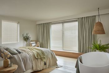 faux wood Venetian blinds fitted to two windows in a bedroom decorated in white and natural wood colours