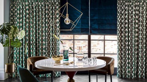 emerald and gold curtains on a large window paired with teal roman blinds in a dining room