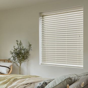 Zen whisper faux wooden blind in small bedroom window with olive tree