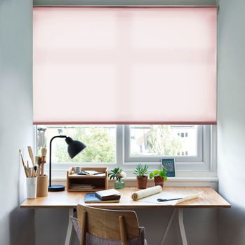 Reber Blush Roller Blind with a desk in front of the window and a lamp on the table and office stationary