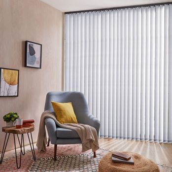 Reber Silver vertical blinds in a living nook with a blue chair in the center with a yellow pillow and pink blanket on it