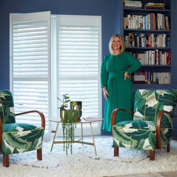Erica Davies in a living room with white full height shutters, armchairs, rug and side table