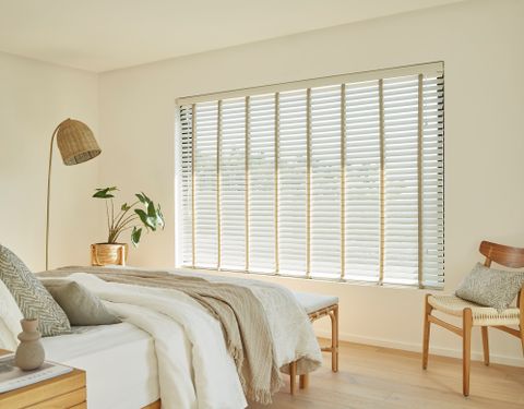 white coloured wood venetian blinds fitted to a large window in a bedroom decorate with wood and white