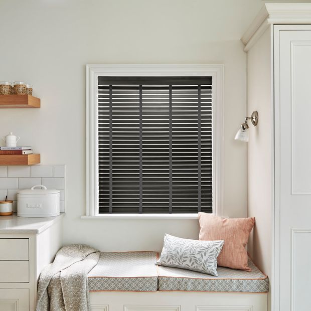 Faux wood venetian blinds with tapes in obsidian black shade above furnished window ledge