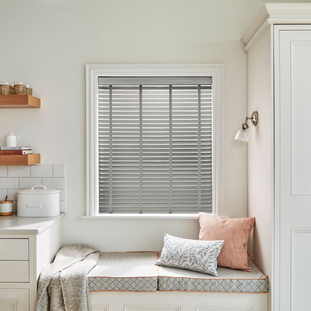 Faux wood venetian bamboo blinds in silver grey on a kitchen window above furnished window ledge