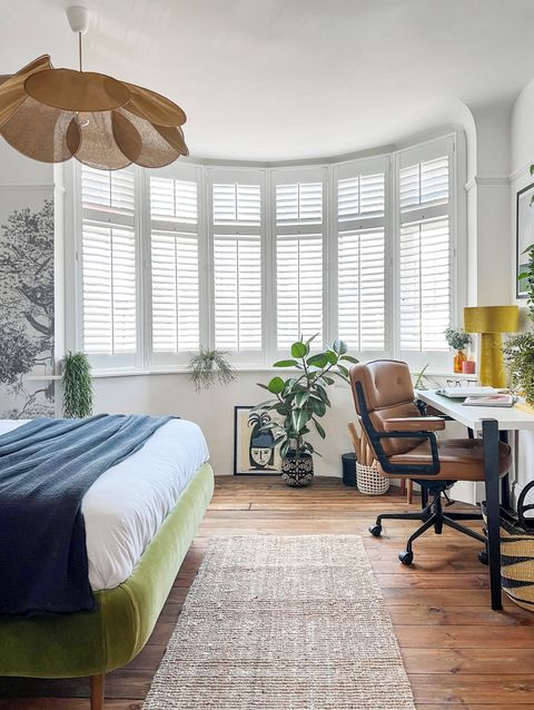Pure White shutters in a bedroom with the bed to the left and a desk and chair to the right and a rug in the middle