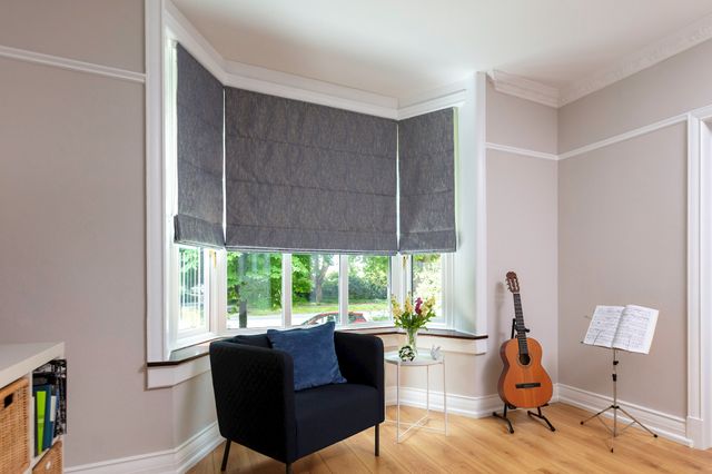 Surface blue roman blinds fitted to a bay window in a living room