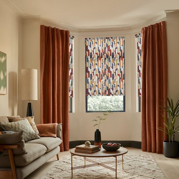 Bauhaus sandstone roller blinds paired with surface spice curtains on a living room bay window